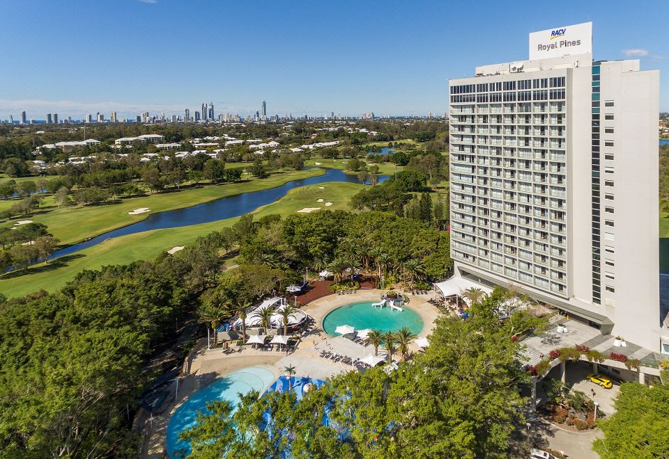 a hotel with a pool and lush greenery is surrounded by trees , with a golf course nearby at Racv Royal Pines Resort Gold Coast