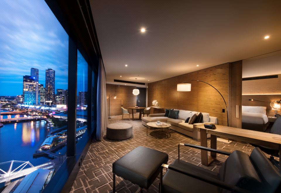 a luxurious hotel room with large windows offering a view of the city , modern furniture , and comfortable seating arrangements at Pan Pacific Melbourne
