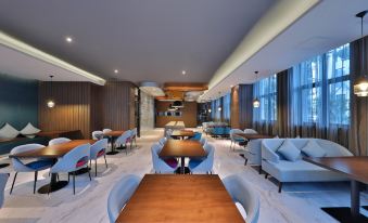 The restaurant features spacious tables and chairs arranged in the center, complemented by an open concept living area at Orange Hotel (Shanghai Pudong Airport)