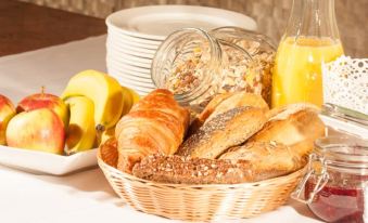 a basket filled with various types of bread , including croissants , bagels , and muffins , placed on a dining table at LUDWIGS