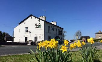 "a white building with yellow flowers in front of it and a sign that says "" rylsk ""." at The Punchbowl Hotel