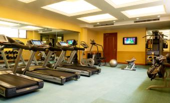 A spacious room with exercise equipment, including an indoor treadmill, situated in the center on a tiled floor at Merchant Marco Hotel
