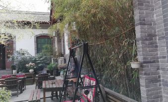 There is a small patio with chairs and tables located in the middle, adjacent to an outdoor seating area at 7 Sages International Youth Hostel