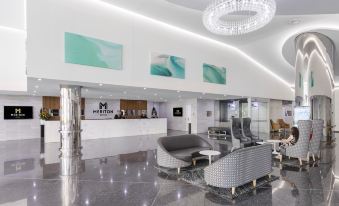 a modern hotel lobby with a marble floor , white walls , and a reception desk area at Meriton Suites Southport