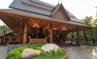 a large wooden building with a sign on the front , surrounded by lush greenery and rocks at Khum Wang Nuea Villa