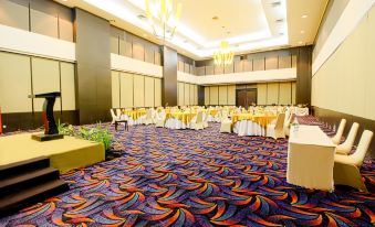 a large , well - lit banquet hall with multiple dining tables and chairs arranged for a formal event at Sahid Bela Ternate
