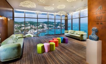 a modern living room with large windows offering a view of the ocean , wooden floors , and colorful furniture at Dongji Island Dongguan Hotel