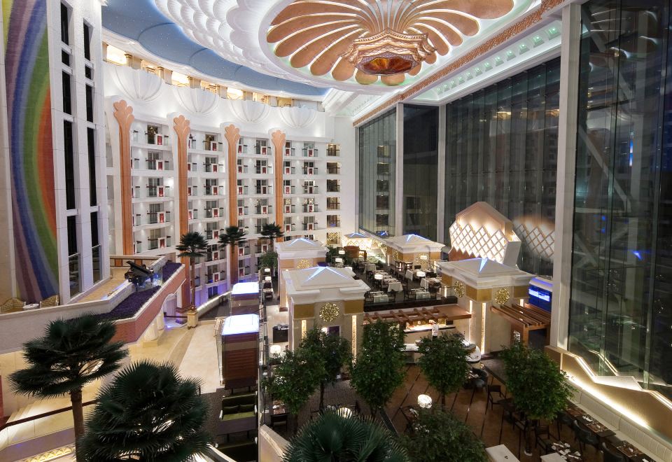 a large hotel lobby with high ceilings , multiple seating areas , and a dining area under a unique decorative ceiling at Central Hotel