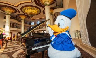 A large statue sits in front of a person playing an instrument on stage at Shanghai Disneyland Hotel