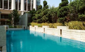 Next to an apartment complex, there is a swimming pool with blue water and trees in the background at Hotel Alexandra
