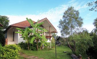 a house with a red roof is surrounded by greenery and trees , under a clear blue sky at Baan Suan Nuanta