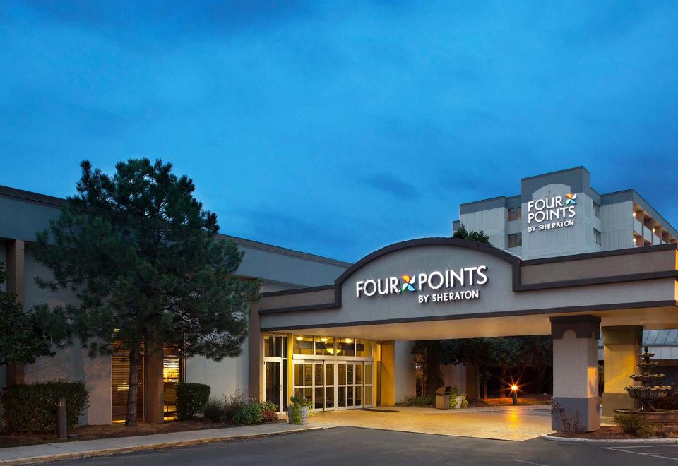 a large hotel with a four points by sheraton sign on the front , surrounded by trees at Four Points by Sheraton Chicago O'Hare