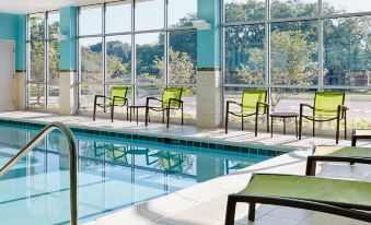 an indoor swimming pool with several chairs placed around it , providing a relaxing atmosphere for swimmers at SpringHill Suites Oklahoma City Downtown/Bricktown