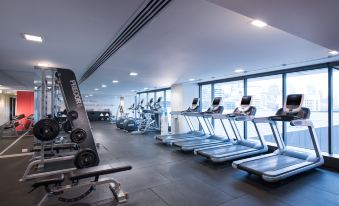 a gym with various exercise equipment , including treadmills and stationary bikes , as well as a window in the background at Pan Pacific Melbourne