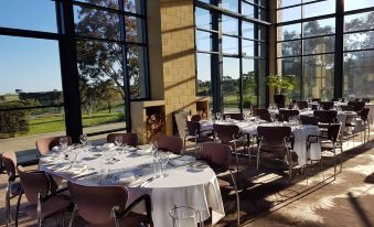 a large dining room with multiple tables set for a formal meal , surrounded by windows and a fireplace at Aitken Hill