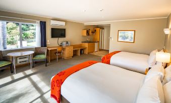 a hotel room with two beds , a desk , and a flat - screen tv mounted on the wall at Scenic Hotel Bay of Islands
