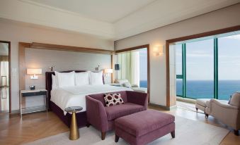 a luxurious hotel room with a large bed , a purple couch , and a balcony overlooking the ocean at Condado Vanderbilt Hotel