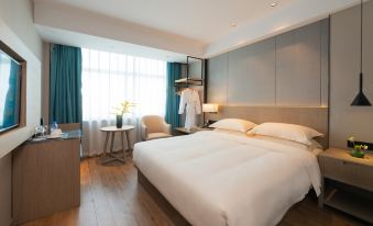 There is a bedroom with a double bed, a large window, and a white chair at Yiwu Mankalan Hotel (International Trade City Xinguanghui Branch)