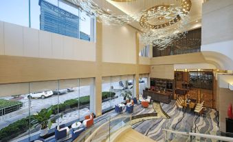 The hotel lobby features a large window with floor-to-ceiling windows that provide a view of other rooms at Qingdao  Litian Hotel