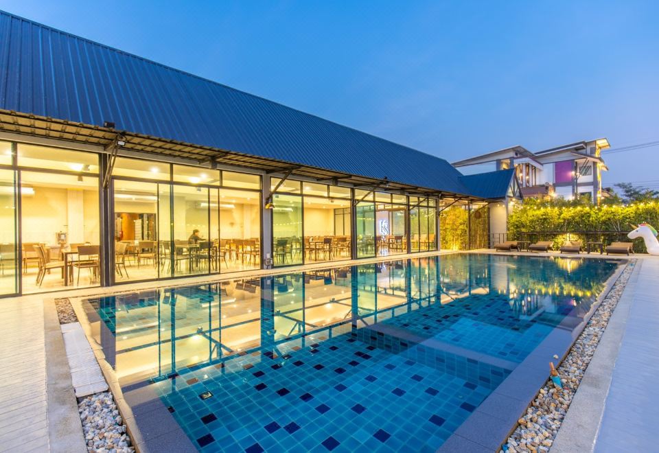 a large swimming pool is surrounded by a building with glass walls and a tiled roof at KS Hotel
