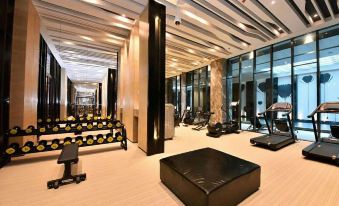 a modern gym with various exercise equipment , including treadmills and weight machines , arranged in a spacious room at The One Hotel
