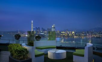 The apartment offers a balcony with chairs and tables that provide a view of the city at night at The Park Lane Hong Kong a Pullman Hotel