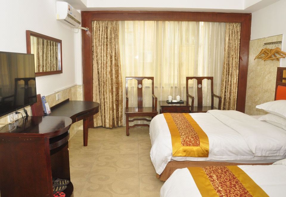 There is a room with two beds, a desk, and a chair located on the far side at Tongtong Hotel