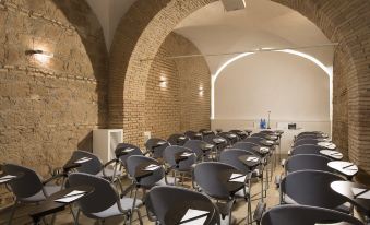 an empty conference room with rows of chairs and papers on the desk , under an arched ceiling with exposed brick walls at Rome Times Hotel