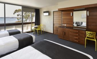 a modern hotel room with two beds , a desk , and a balcony offering a view of the city at Bayside Hotel