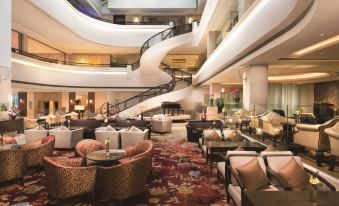 The hotel lobby features spacious tables and chairs, as well as a spiral staircase leading to an additional room at Shangri-La Shenzhen Hotel