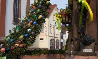 "a beautiful christmas tree decorated with colorful ornaments , standing in front of a building that has the name "" hotel "" written on it" at LUDWIGS