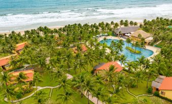 an aerial view of a resort with a swimming pool surrounded by palm trees and grass , located near the ocean at Pandanus Resort