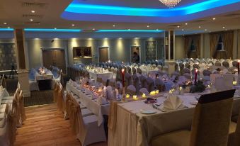 a large dining room with multiple tables set for a formal event , adorned with white tablecloths and gold chairs at Breffni Arms Hotel