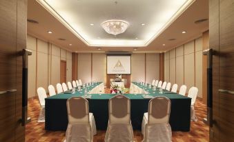 a long conference table with white chairs and green tablecloths is set up in a room at Cititel Penang