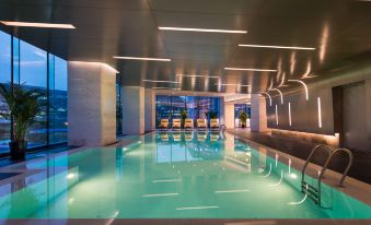 The interior of the hotel includes a spacious indoor pool and lounge area, along with a separate room for relaxation at Novotel Shanghai Hongqiao