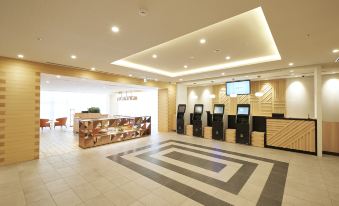 The hotel features a spacious lobby with a centrally located ATM machine and reception desk, all adorned with tiled flooring at Sotetsu Fresa Inn Osaka Namba
