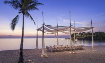 a beach wedding setup with a canopy , tables , and chairs under the setting sun , overlooking the ocean at Shangri-La Boracay