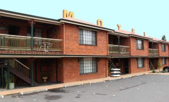 a brick building with multiple stories , possibly a motel or apartment complex , located on a city street at Poet's Recall Motel