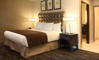 a large bed with a brown blanket and white pillows is in a hotel room at DoubleTree by Hilton Claremont