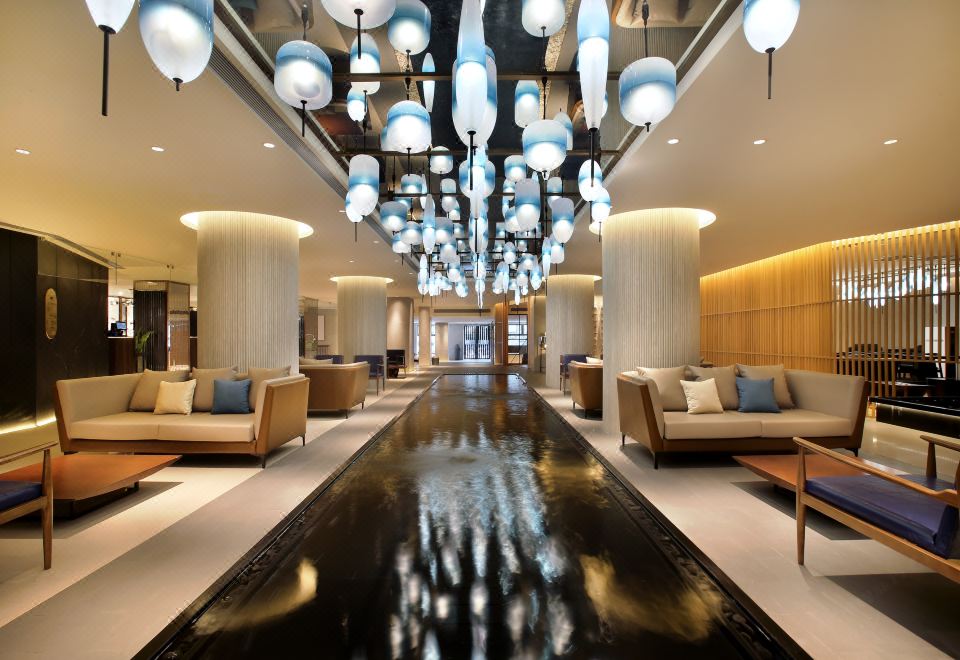 The lobby features ceiling lights and an atrium that provides access to other areas at Ginco Hotel