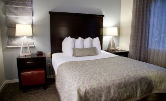 a large bed with a wooden headboard and white pillows is in a hotel room at Sonesta ES Suites San Francisco Airport San Bruno