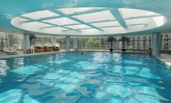 The hotel in Kuala Lumpur offers an indoor pool with clear blue water and a scenic view through the window at Grand Millennium Shanghai HongQiao