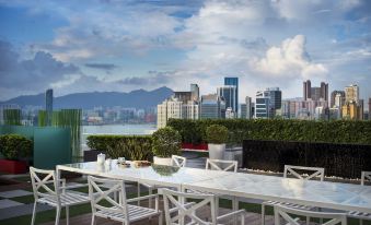 There is a table and chairs on the roof, providing a view of an outdoor terrace with city views in the background at The Park Lane Hong Kong a Pullman Hotel