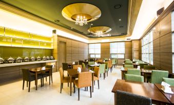a modern , well - lit restaurant with wooden tables and chairs , green upholstered chairs , and large windows at Polaris Hotel