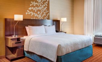 a large bed with white linens and a blue skirt is situated in a hotel room at Fairfield by Marriott San Salvador