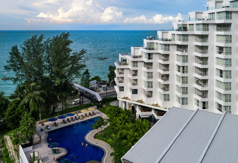 a luxurious resort with multiple buildings and a pool , surrounded by palm trees and overlooking the ocean at DoubleTree Resort by Hilton Hotel Penang