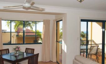 a dining room with a table and chairs , a couch , and a sliding glass door leading to a balcony at Mediterranean Resorts
