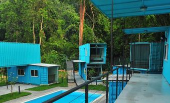 a blue house surrounded by trees , with a swimming pool in front of it at Sarang by the Brook