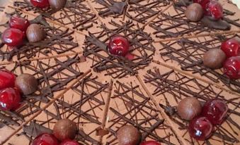 a large chocolate cake with cherries and chocolate drizzle , sitting on a dining table in front of a white tablecloth at LUDWIGS