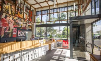 a modern office building with large windows , a reception area , and various advertising materials on the walls at YHA Byron Bay